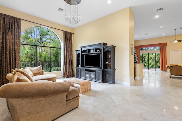 living room with a wealth of natural light and ceiling fan with notable chandelier