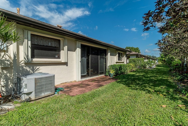 rear view of property with a lawn and cooling unit