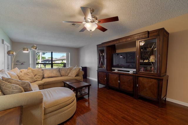 living room with a textured ceiling, dark wood-type flooring, and ceiling fan