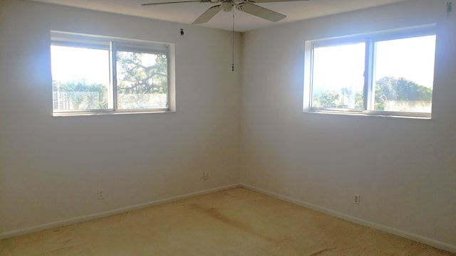 empty room featuring ceiling fan, light carpet, and a wealth of natural light