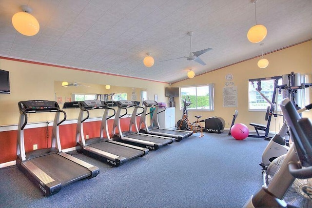 workout area with ceiling fan, ornamental molding, and vaulted ceiling