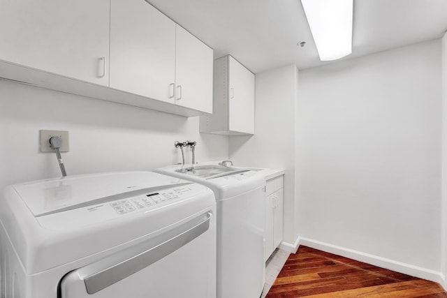 laundry area with wood-type flooring, washing machine and dryer, and cabinets