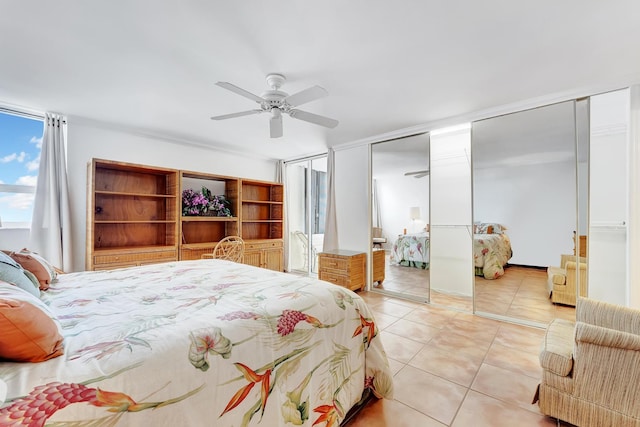 tiled bedroom with ceiling fan and two closets