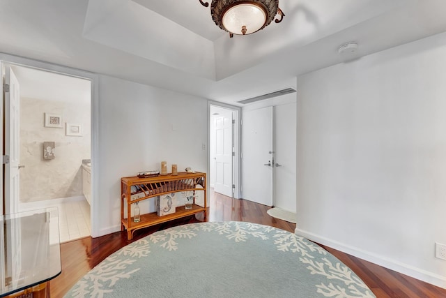 bedroom with connected bathroom and hardwood / wood-style floors