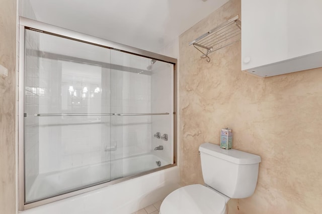 bathroom featuring toilet and combined bath / shower with glass door