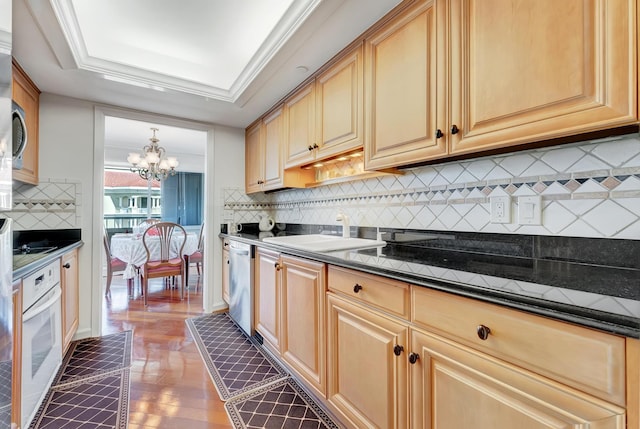 kitchen featuring oven, sink, stainless steel dishwasher, decorative backsplash, and a chandelier