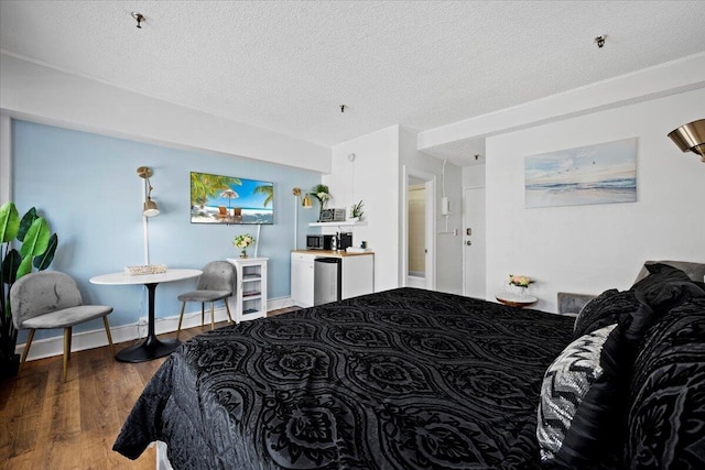 bedroom with fridge, a textured ceiling, and dark hardwood / wood-style flooring