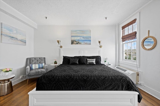 bedroom featuring hardwood / wood-style flooring, a wall mounted AC, and a textured ceiling