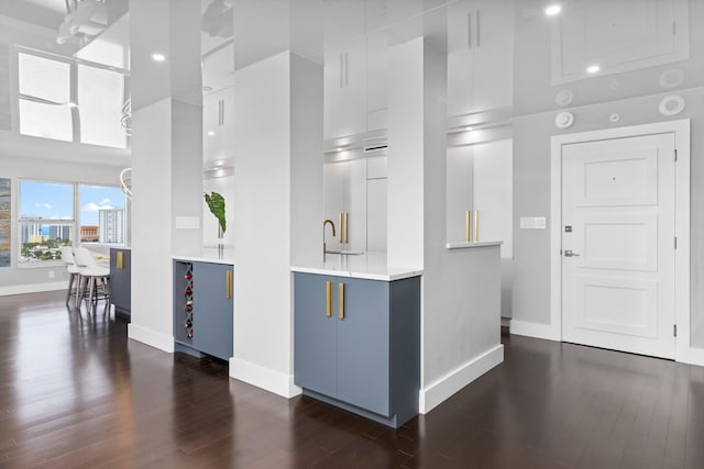 kitchen featuring a towering ceiling, sink, dark hardwood / wood-style flooring, white cabinetry, and a chandelier