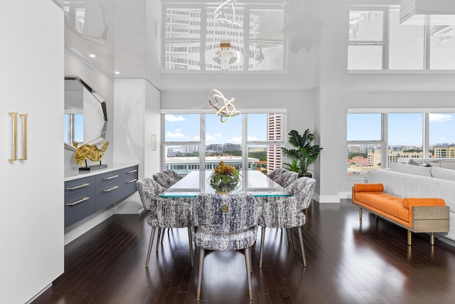 dining room with a high ceiling, dark hardwood / wood-style floors, and an inviting chandelier