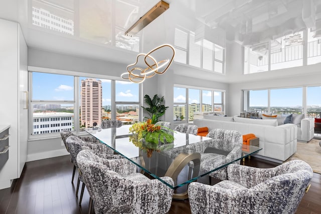 dining area with dark wood-type flooring, a towering ceiling, and plenty of natural light