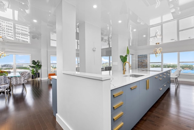 875 E Camino Real Unit 16H & G, Boca Raton, FL 33432 - kitchen with a high ceiling, a sink, blue cabinetry, baseboards, and dark wood-style floors