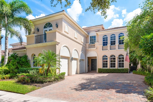 mediterranean / spanish-style house with a balcony, central AC unit, and a garage