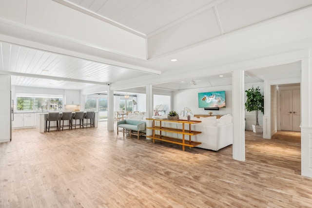 living room featuring beamed ceiling and light hardwood / wood-style floors