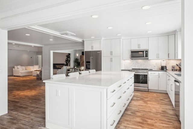 kitchen with a kitchen island, white cabinets, light hardwood / wood-style floors, and stainless steel appliances