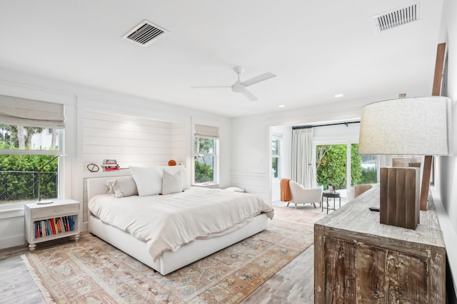 bedroom with ceiling fan, multiple windows, and light hardwood / wood-style floors