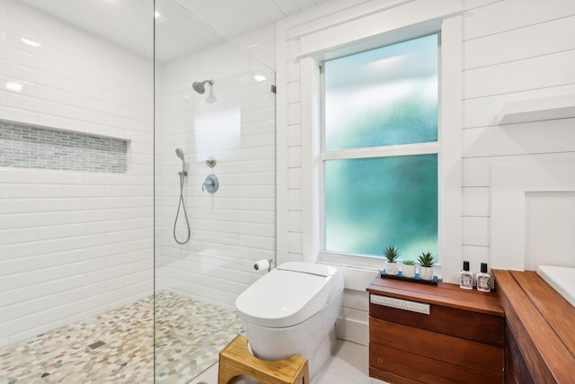 bathroom with a tile shower and toilet