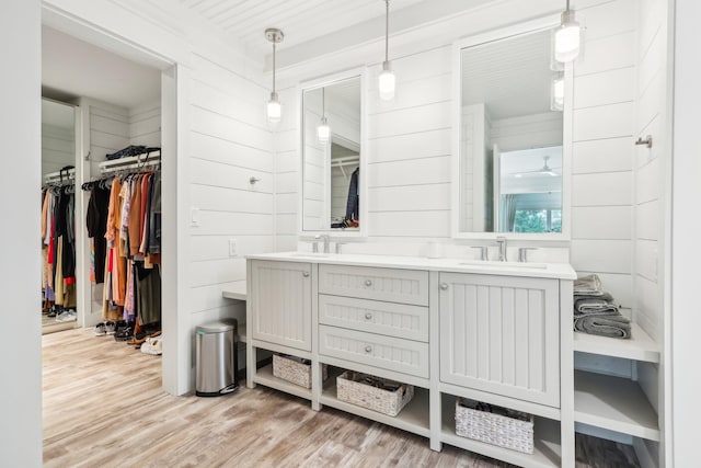 bathroom with wood walls, wood-type flooring, and vanity