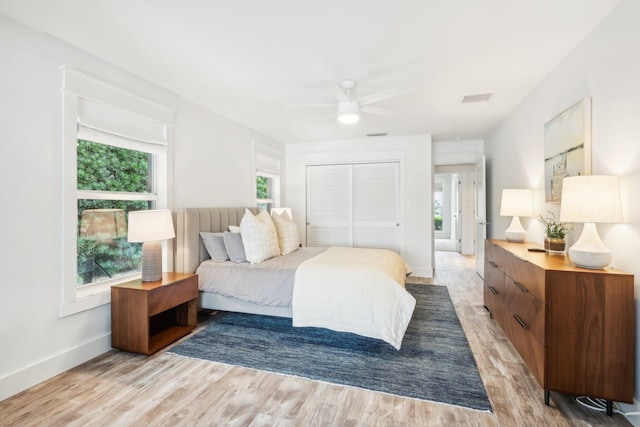 bedroom featuring light hardwood / wood-style floors, ceiling fan, and a closet