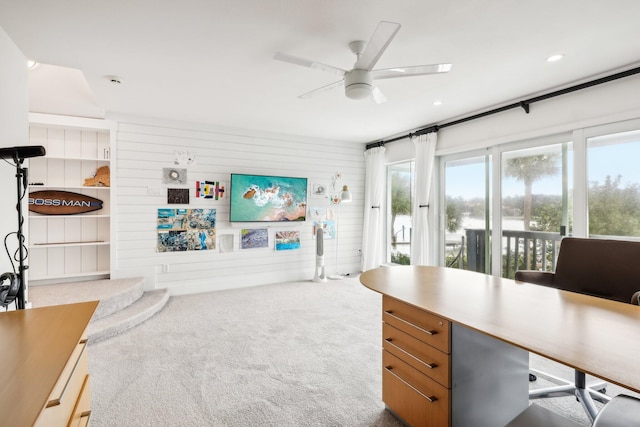 carpeted office with wood walls and ceiling fan