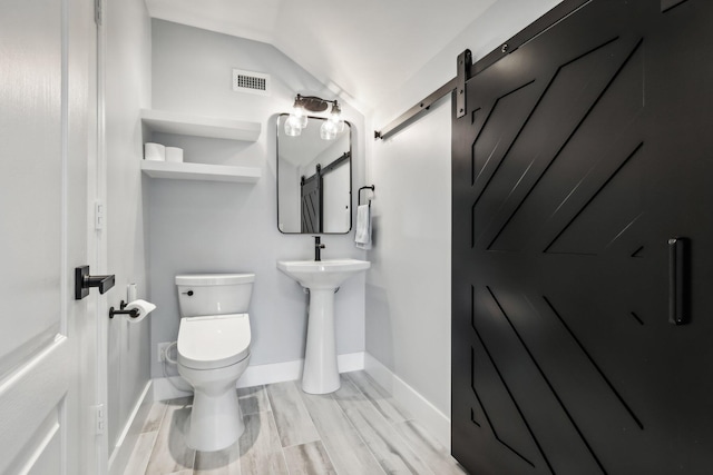 bathroom featuring toilet, vaulted ceiling, and wood-type flooring