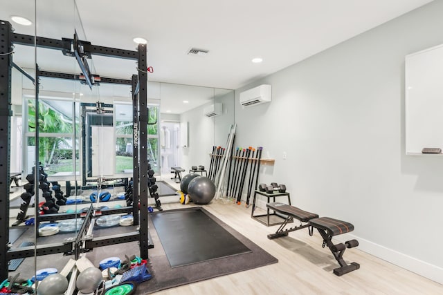 workout area featuring a wall mounted air conditioner and light hardwood / wood-style flooring