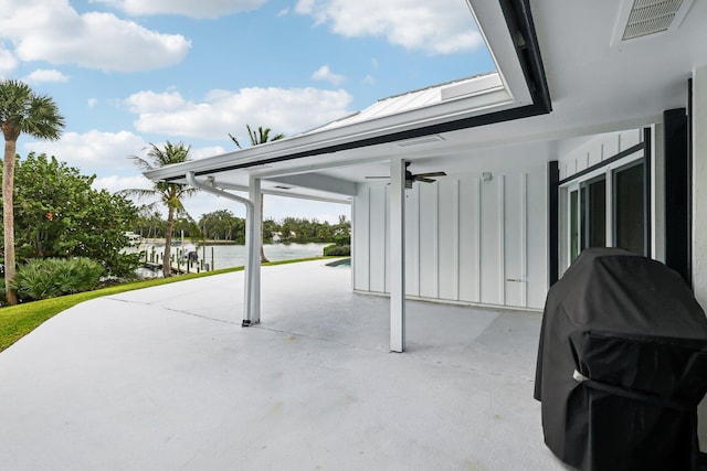 view of patio with ceiling fan, a grill, and a water view