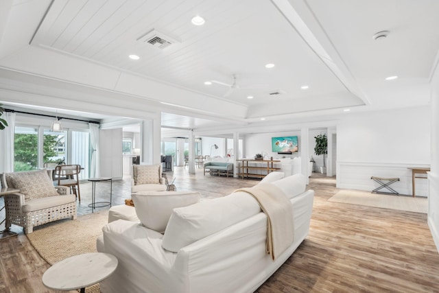 living room featuring light hardwood / wood-style floors, ceiling fan, and a raised ceiling