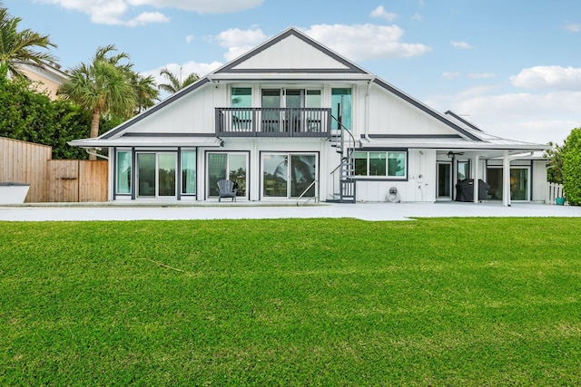 rear view of house with a lawn, a balcony, and a patio area