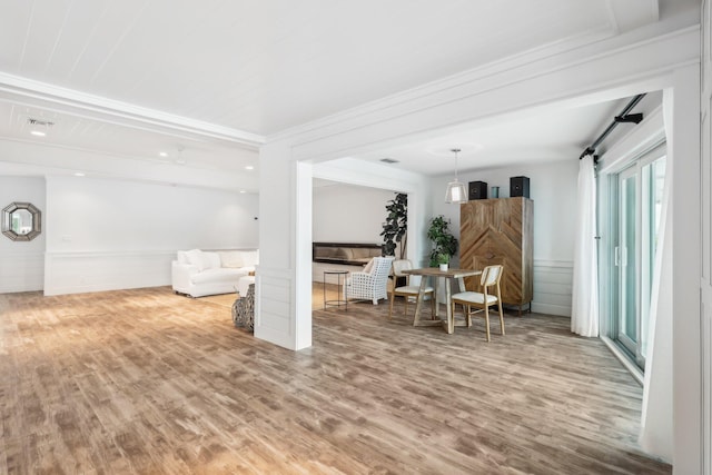 living room featuring a barn door, wood-type flooring, and ornamental molding