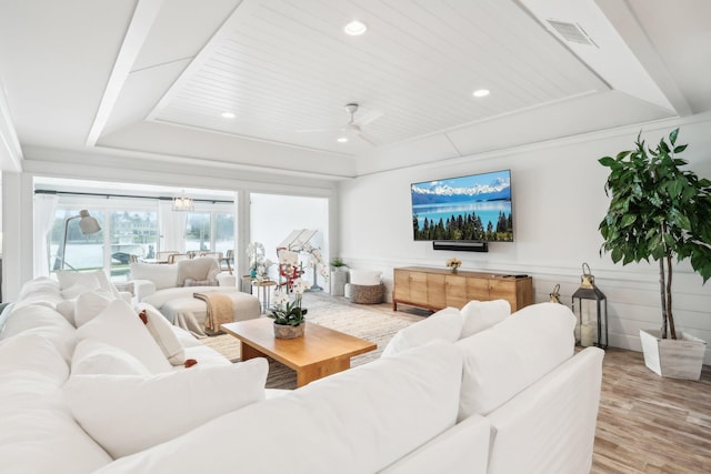 living room featuring hardwood / wood-style flooring, ceiling fan, and a raised ceiling