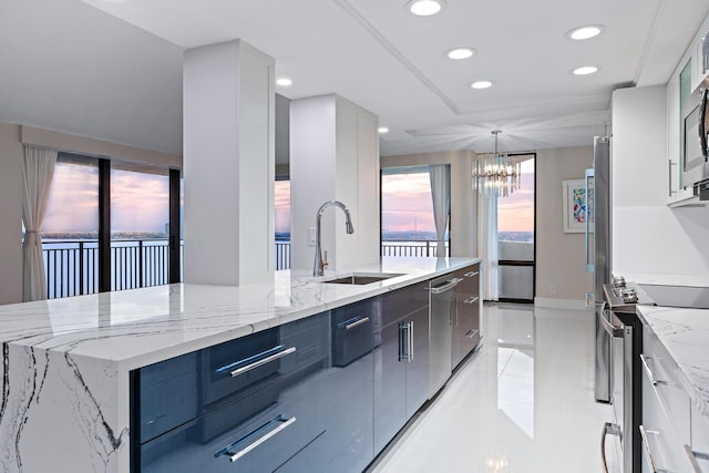 kitchen with decorative light fixtures, stainless steel appliances, white cabinetry, and sink