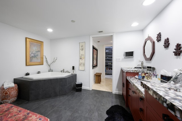 bathroom with vanity, tiled bath, and tile patterned flooring