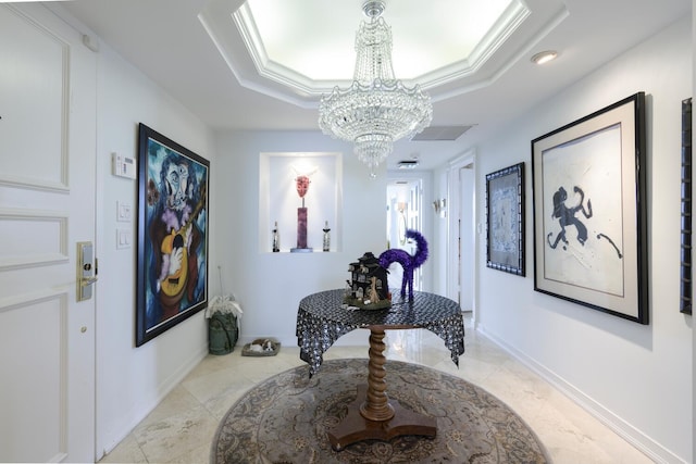 hallway featuring an inviting chandelier, ornamental molding, a tray ceiling, and light tile patterned floors