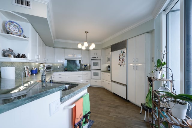 kitchen with white cabinetry, a chandelier, ornamental molding, dark hardwood / wood-style floors, and white appliances