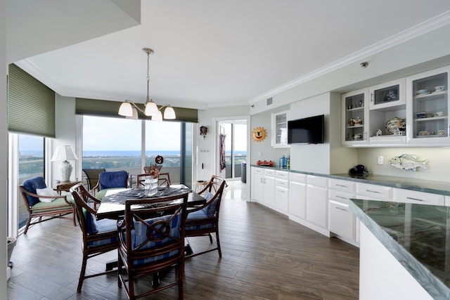 dining space with an inviting chandelier, ornamental molding, and dark wood-type flooring