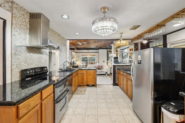 kitchen featuring pendant lighting, sink, wall chimney range hood, appliances with stainless steel finishes, and dark stone countertops