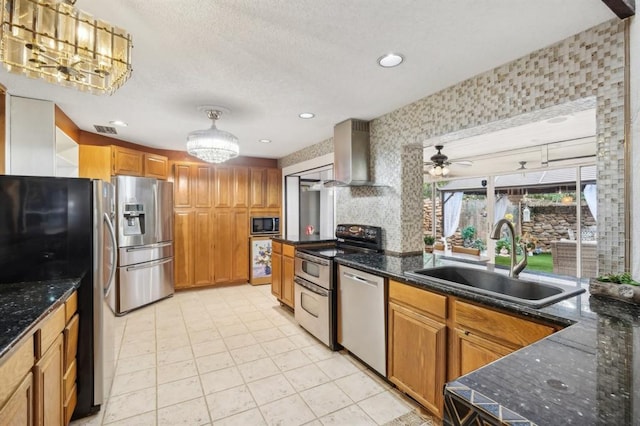 kitchen with wall chimney range hood, ceiling fan, decorative light fixtures, sink, and stainless steel appliances