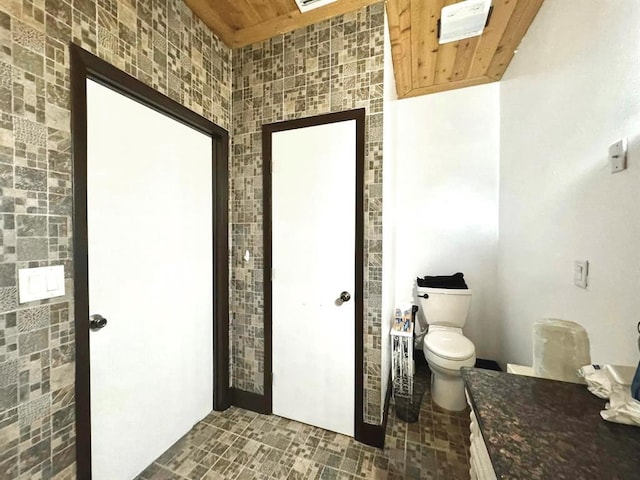 bathroom featuring tile walls, wooden ceiling, and toilet