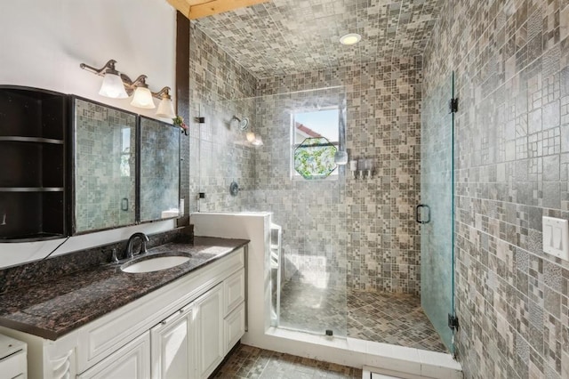 bathroom with a shower with door, vanity, and tile walls