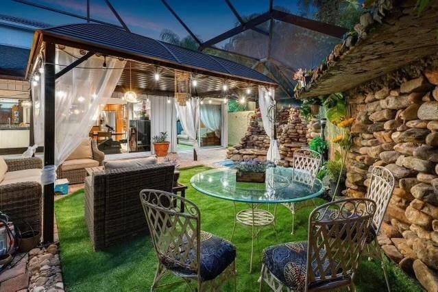 patio terrace at dusk with an outdoor living space, a yard, and a lanai