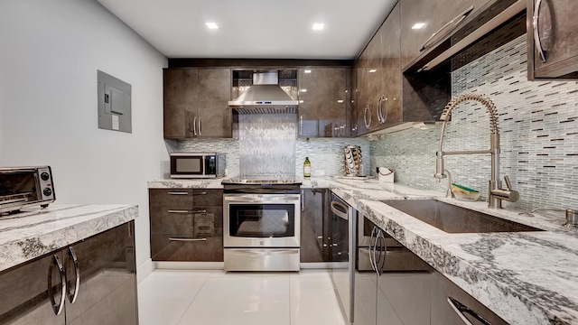 kitchen featuring wall chimney range hood, sink, decorative backsplash, appliances with stainless steel finishes, and light stone counters