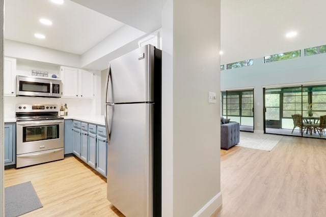 kitchen with stainless steel appliances, light hardwood / wood-style flooring, and white cabinetry