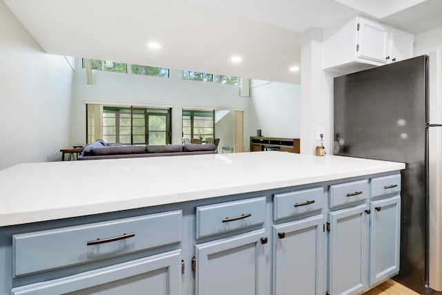 kitchen featuring light hardwood / wood-style floors, white cabinets, and black refrigerator