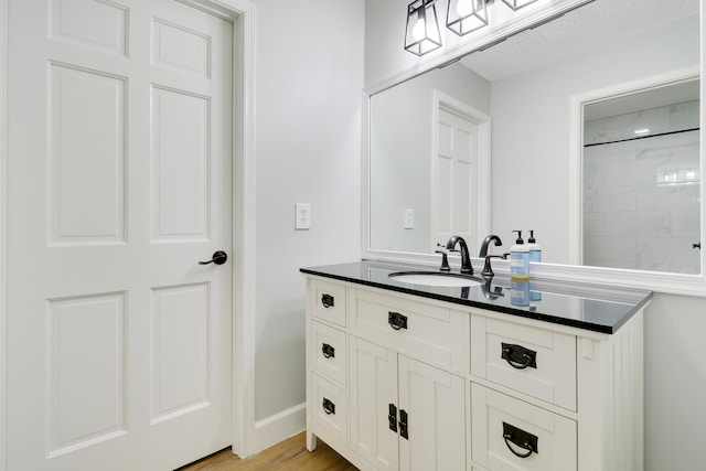 bathroom with walk in shower, vanity, and hardwood / wood-style flooring