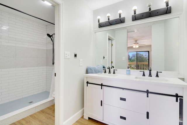 bathroom with a tile shower, vanity, hardwood / wood-style floors, and a textured ceiling