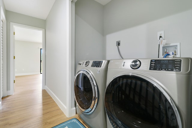 laundry area featuring independent washer and dryer and light hardwood / wood-style flooring