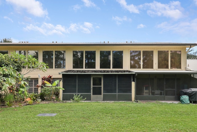 rear view of property featuring a yard and a sunroom