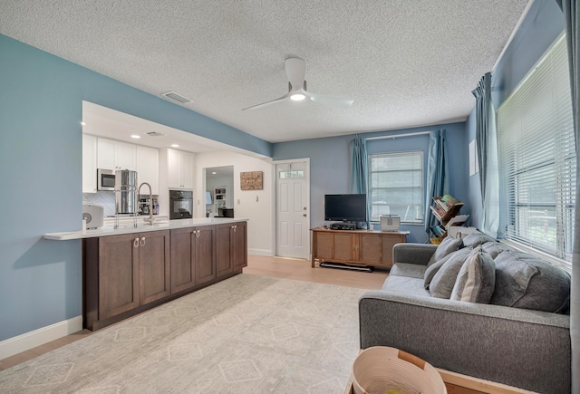 living room featuring ceiling fan, sink, and a textured ceiling