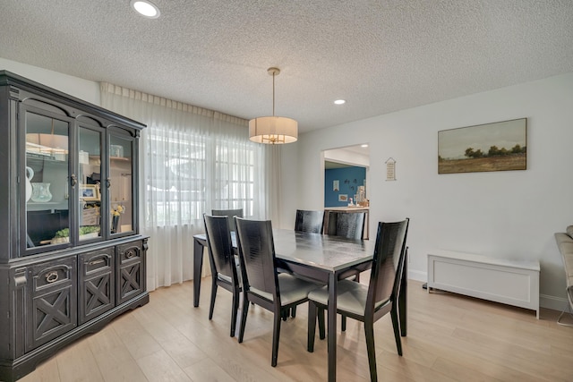 dining area with light wood-type flooring and a textured ceiling